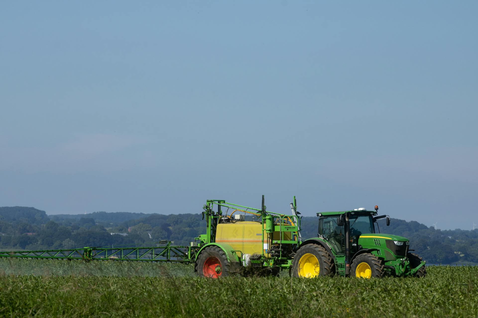 Photo d'un paysage avec un tracteur répandant des pesticides sur un champ.