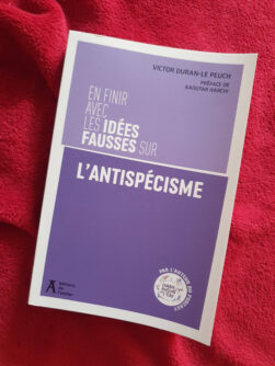 Couverture violette du livre « En finir avec les idées fausses sur l’antispécisme » par Victor Duran le Peuch, posé sur un plaid rouge.
